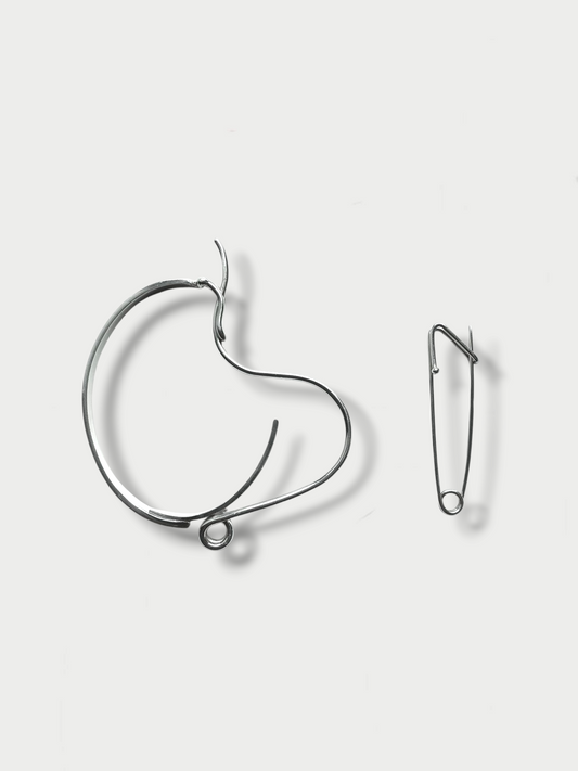Anthony Was Here Experimental silver bracelet placed next to a safety pin for design inspiration and scale