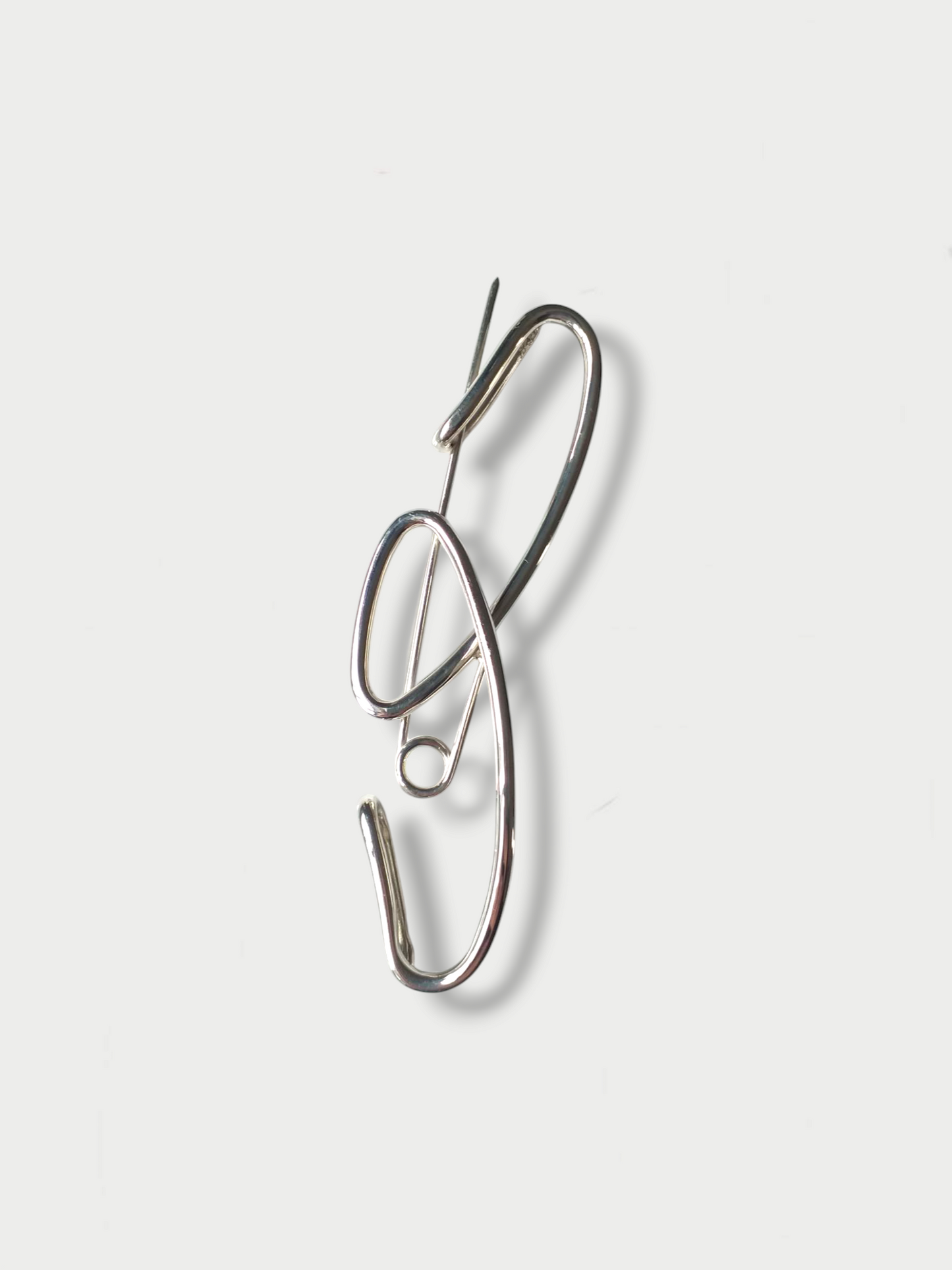 A silver brooch with a simple art deco' inspired design on a white background placed vertically
