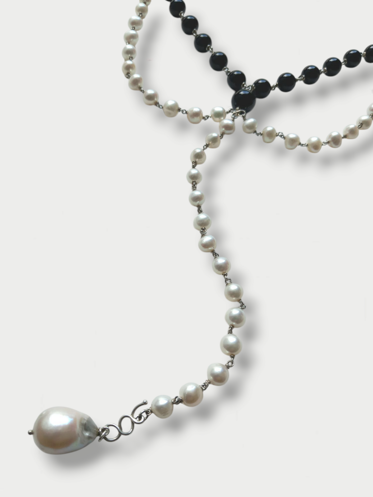 Detail of a black and white composition necklace with pearls and onyx beads, silver (925) detailing, displayed against a white background.