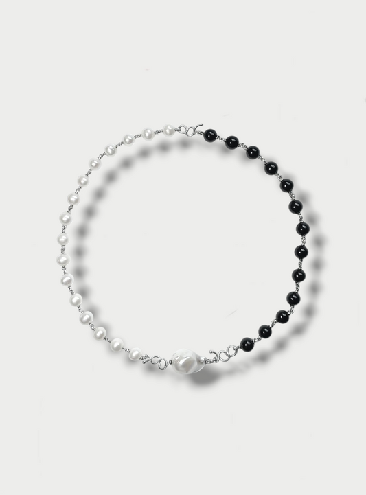 Anthony Was Here two-tone necklace with a combination of pearls and onyx beads, featuring a central baroque pearl, on a white background.