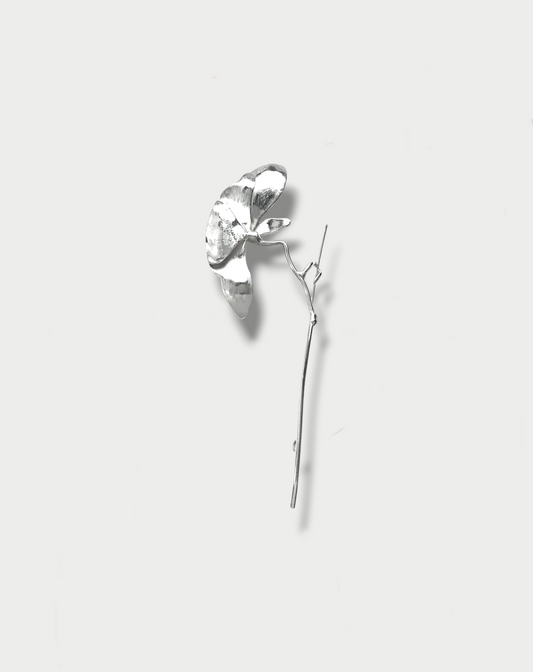 A silver brooch designed to resemble a peony flower on a white background