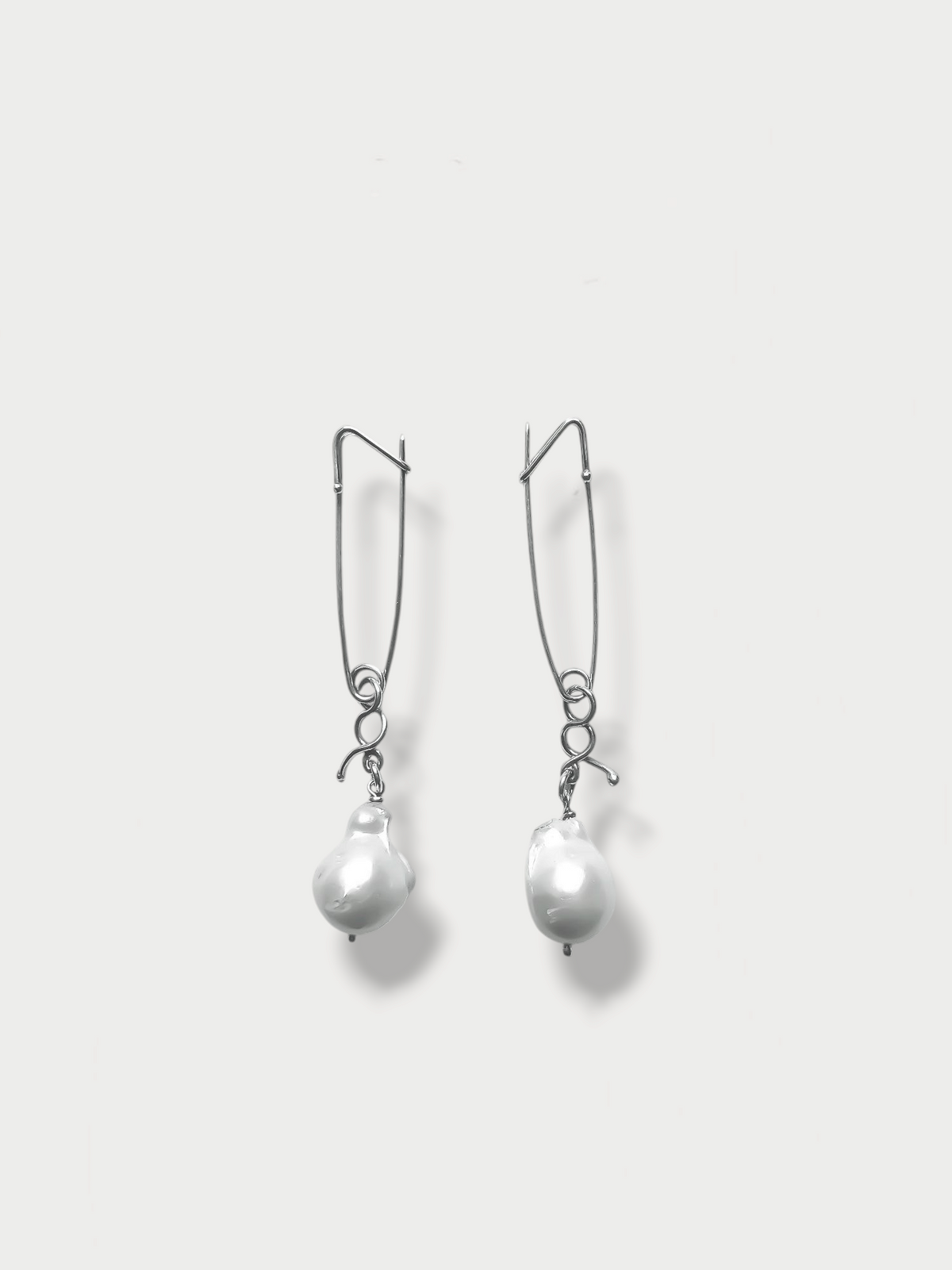 Anthony Was Here pair of silver safety pin cufflinks with pearl drop attachments, displayed against a white background.
