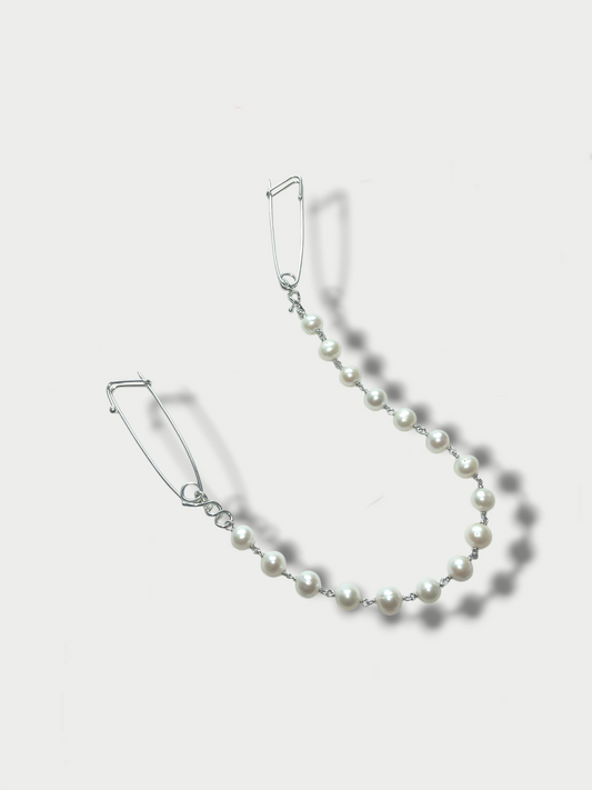 front view of a pin combination on white background formed by two silver (925) safety pin inspired pins connected by a row of pearls